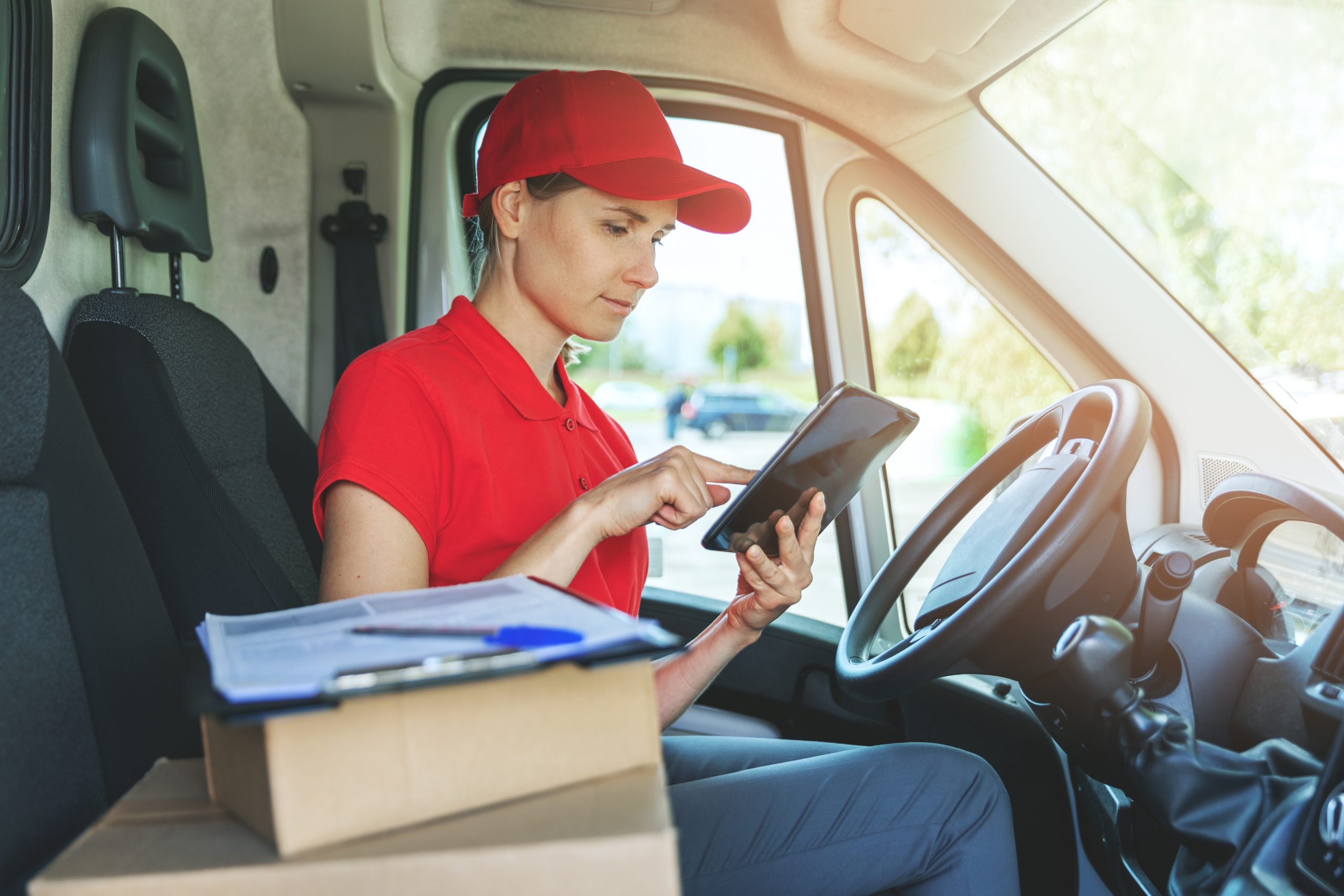 delivery woman using digital tablet while sitting in van