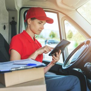 delivery woman using digital tablet while sitting in van